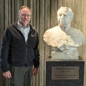 Derek Schuurman standing next to a statue of Abraham Kuyper