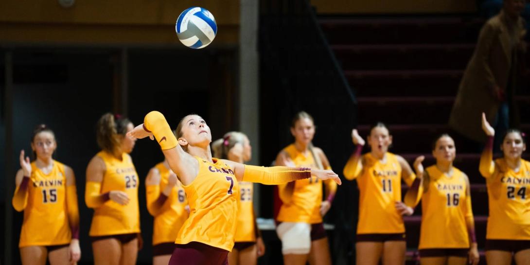 A women's volleyball player at Calvin University serves a ball