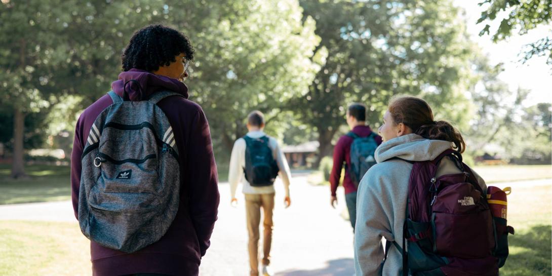 Students walk with backpacks on the Calvin University campus paths.