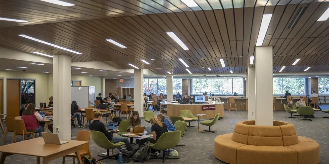 Calvin University students studying in newly-renovated library space, sitting on chairs and reading books