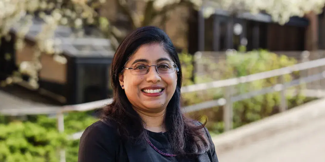 Professor Elizabeth Oommen poses in front of a walkway on Calvin's campus.