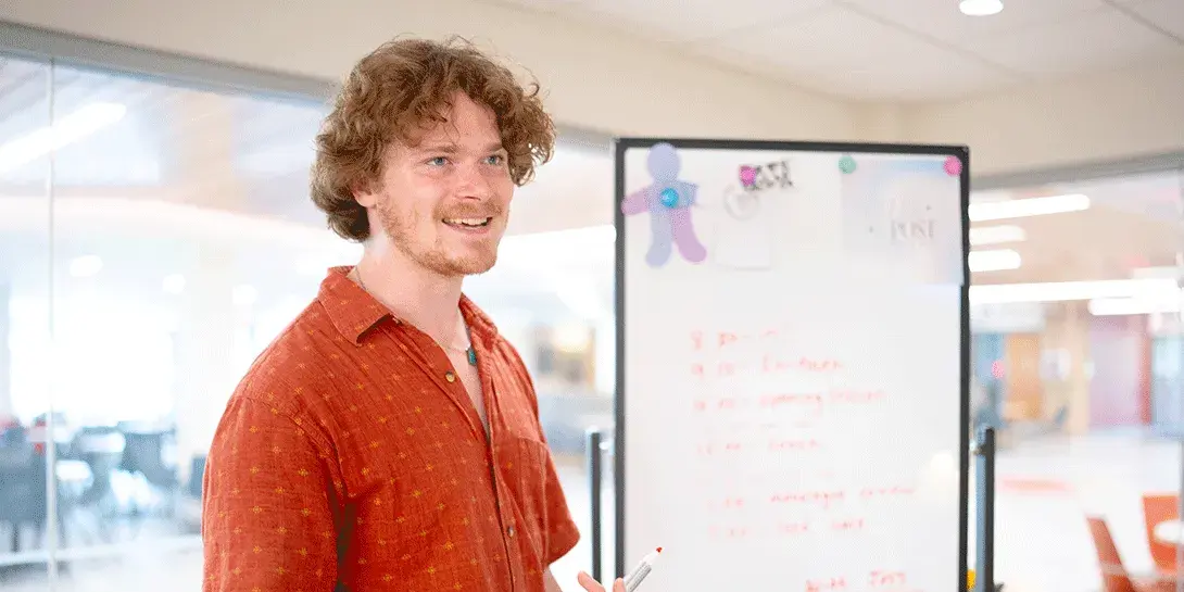 Luke Harlow stands by a whiteboard.