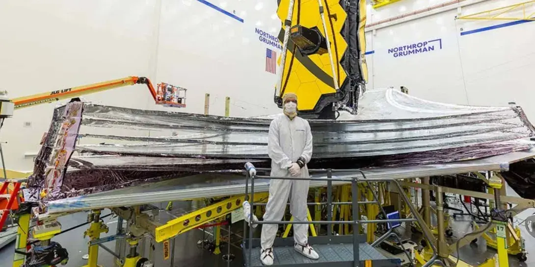 Adam Marquardt standing in the clean room in front of a telescope that's going to be launched into space.