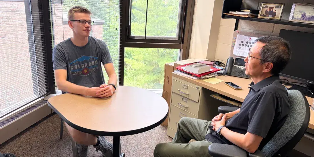 Landon Faber talks with Professor Rocky Chang in his office.