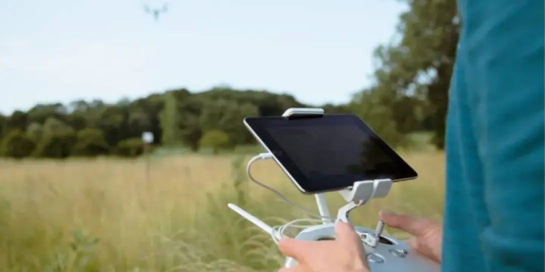 A student flying a drone over an open field.