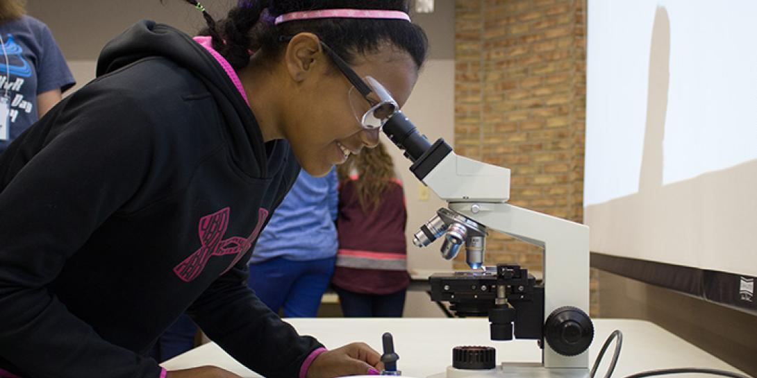 A student looks through a microscope.