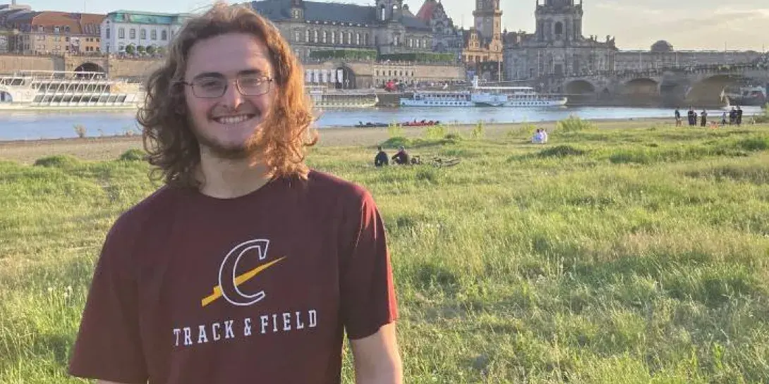 Jonathan Holdridge standing in Europe with a river and buildings behind him.