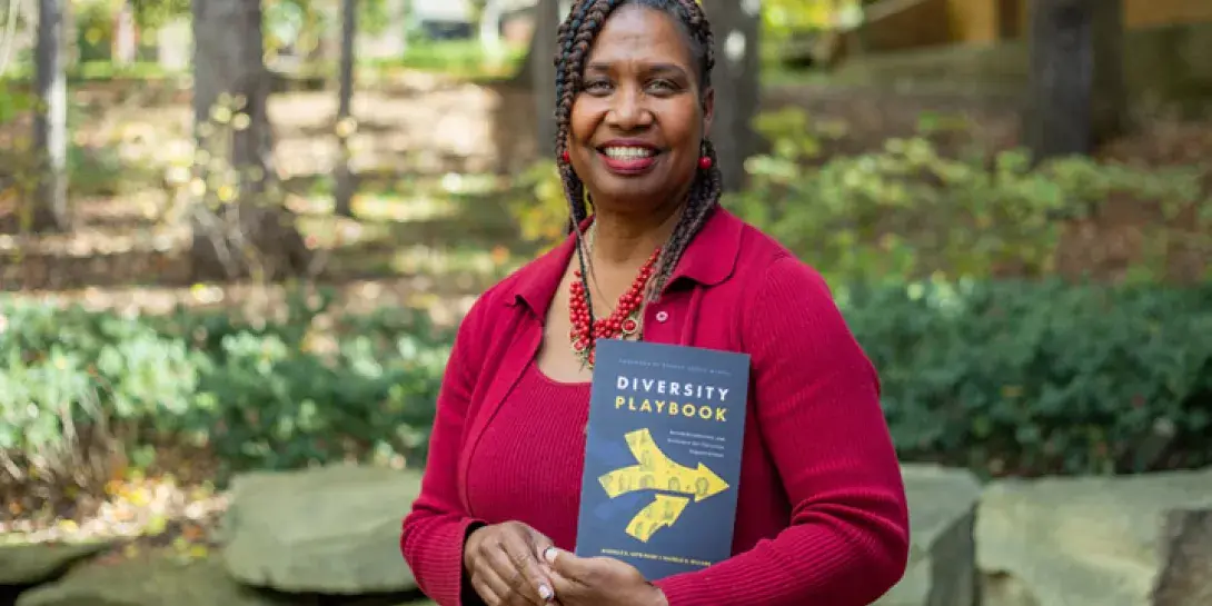 Photo of Michelle Loyd-Paige holding her new book outdoors on Calvin's campus.