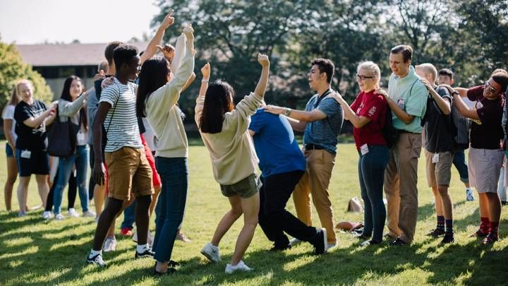 Groups of students stand in a line cheering during a game on the Commons Lawn.