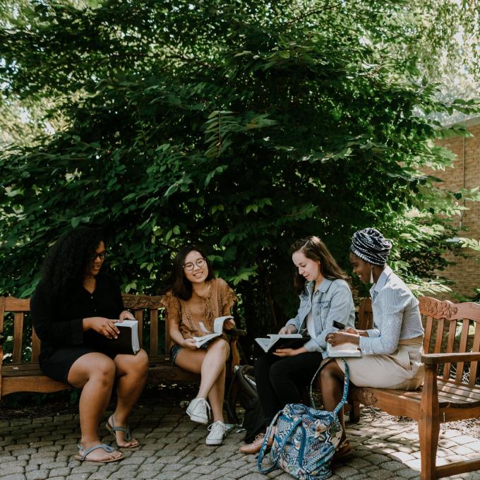 group of students talking to each other on a bench