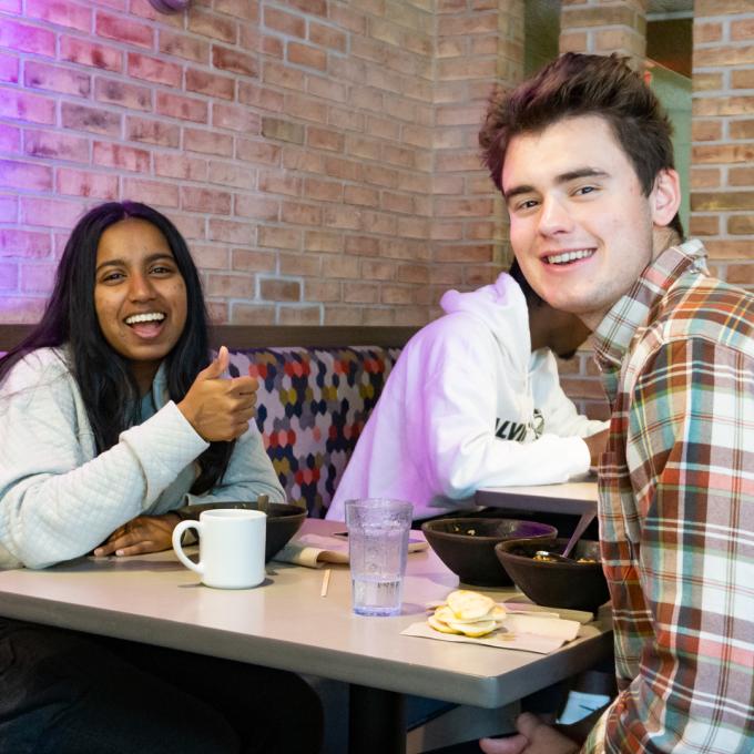 Two students in Commons face camera posing with smiles.