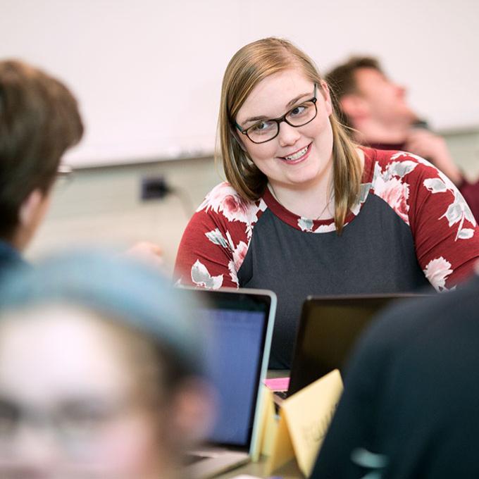Female Calvin student talking with another student in a class with laptops in front of them