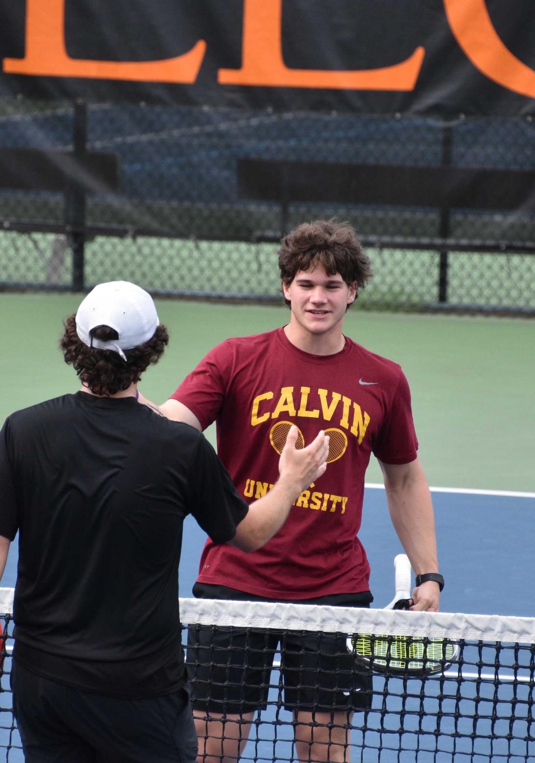 A Calvin men's tennis athlete high fives his opponent after the match.