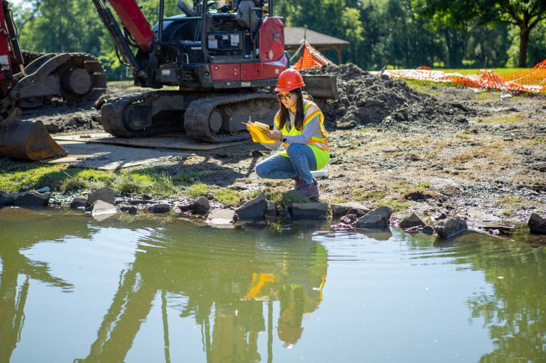 An engineering student takes measurements at a construction site.