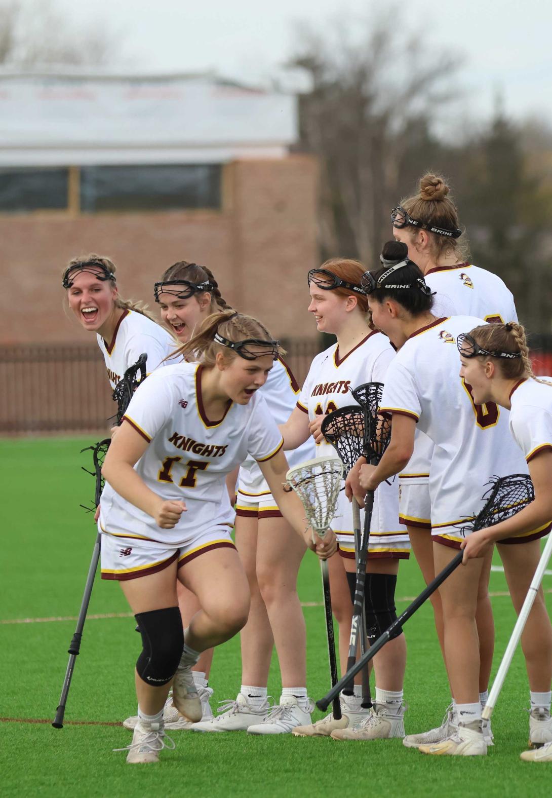 Women's lacrosse players high five as they are announced before the game starts.